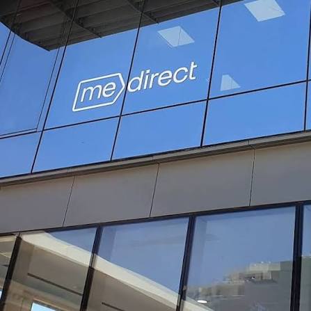 MeDirect logo displayed on the reflective glass exterior of a modern office building.